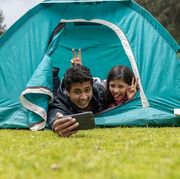 father and daughter taking selfie in camping tent