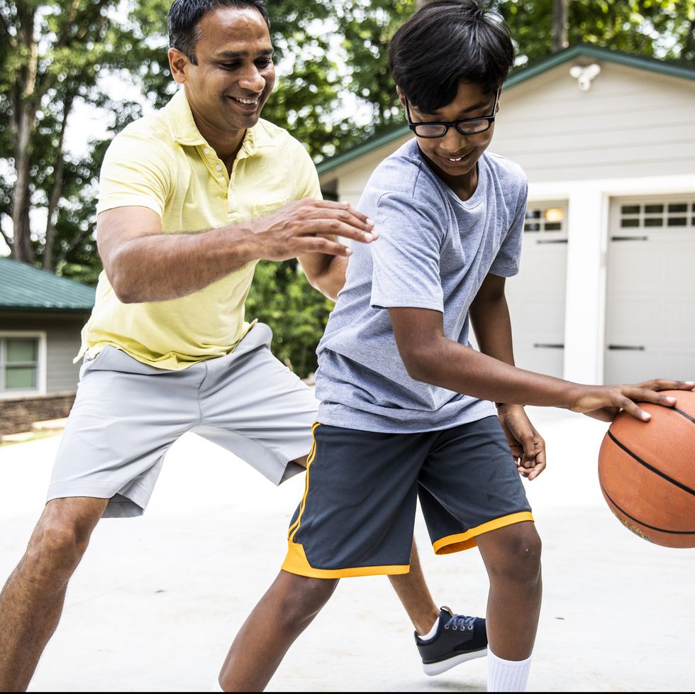 father and son playing basketball in driveway