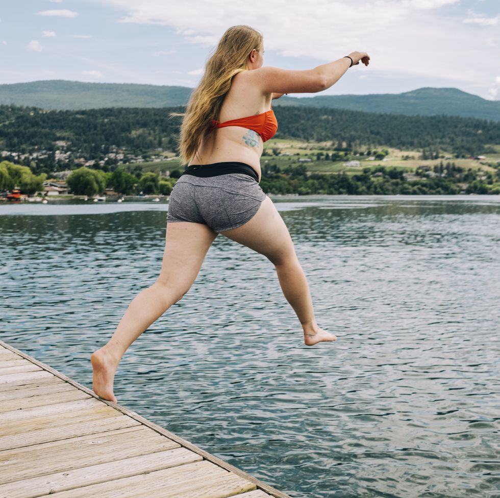 vernon, bc , can june , 24, 2021 a long haired adult women jumps off a dock and into warm waters of kalamalka lake on june 24th, 2021