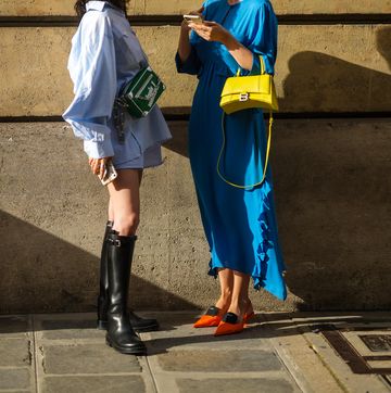 paris, france   july 06 xiayan l wears white sunglasses, a pale blue oversized shirt, pale blue and white striped shorts from lovechild, a green monogram leather crossbody bag from louis vuitton, black shiny leather knees boots  justyna czerniak r wears gold earring, a blue flowing cut out on the chest ruffled long dress, a yellow grained shiny leather handbag from balenciaga, neon orange pointed prada shoes, outside armani, during paris fashion week   haute couture fallwinter 20212022, on july 06, 2021 in paris, france photo by edward berthelotgetty images
