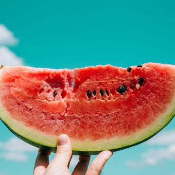 Slice of watermelon in hand slice of watermelon in hand over sky background