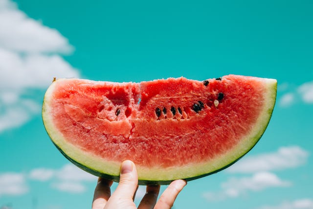 slice of watermelon in hand over sky background