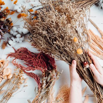 woman composing bouquet of dry flowers and herbs, trendy interior decoration, artisan florist shop idea top view, flat lay