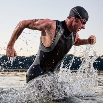 a male triathlete running out of the water un triatleta masculino saliendo del agua después de nadar.