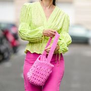 paris, france   august 12 ketevan giorgadze katieone wears neon pink high waisted wide leg denim jeans from zara, a neon green ruffle embroidered low neck v neck blouse with puff sleeves from botrois, a hot pink knit bucket bag with stones from manoush, on august 12, 2021 in paris, france photo by edward berthelotgetty images