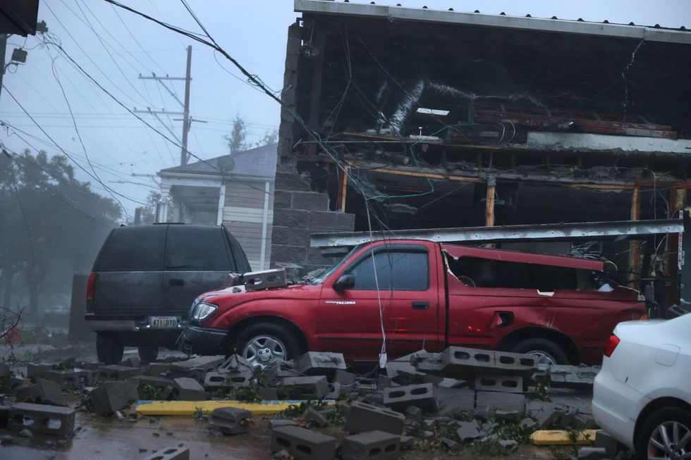 In New Orleans staan beschadigde autos voor de ingestorte pui van een gebouw dat op 29 augustus 2021 tijdens hurricane Ida is ingestort