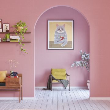 a room with a pink wall and a chair and a shelf with pictures