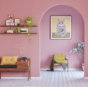 a room with a pink wall and a chair and a shelf with pictures