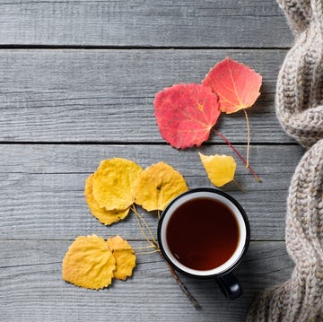Hot coffee or tea in a mug, bright autumn yellow leaves, a warm cozy knitted wool scarf, against the background of an old wooden background or table. The concept of seasonal recreation, relaxation, and peace of mind. Copy of the text space. hot coffee or tea in a mug, bright autumn yellow leaves, a warm cozy knitted wool scarf, against the background of an old wooden background or table the concept of seasonal recreation, relaxation, and peace of mind copy of the text space