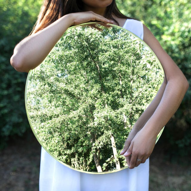 summer portrait of beautiful young asian woman sitting with a mirror in the grass