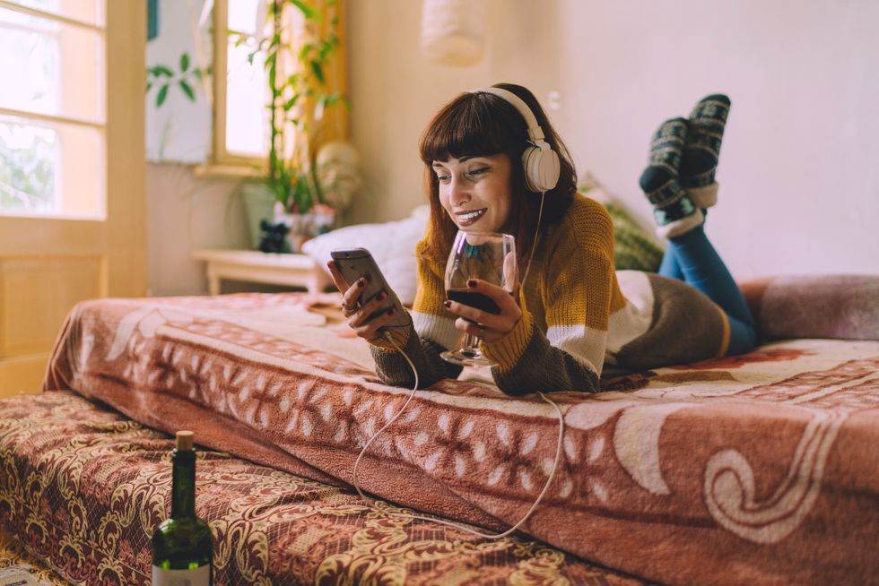 young woman resting in bed and enjoying good music