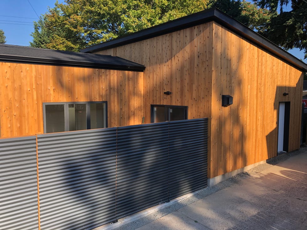 portland, oregon, usa july 9th, 2021 a newly built adu accessory dwelling units with a black metal corrugated fence along an alley