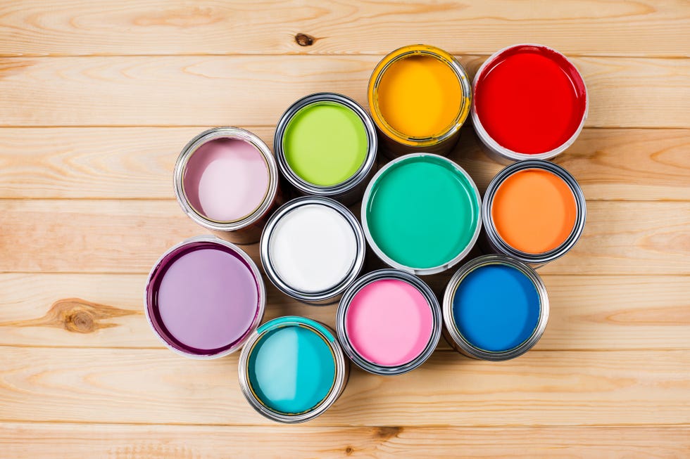 set of open metal buckets with bright multicolored paints ready for renovation works on timber floor. flat lay style. copy space for your design. concept of redecoration in home interior. color swatch for design ideas