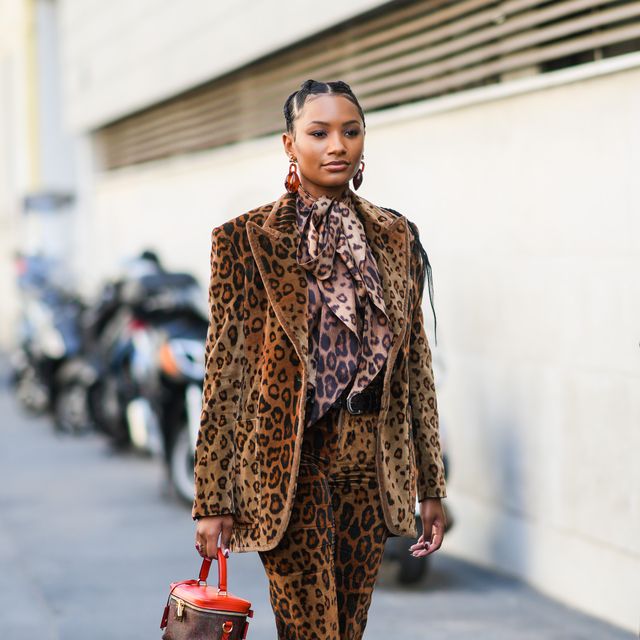 milan, italy   september 23 a guest wears brown large earrings, a black and brown leopard print pattern knotted shirt, a black and brown leopard print pattern velvet blazer jacket, matching black and brown leopard print pattern flared pants, a black shiny leather belt, silver rings, yellow and black leopard print pattern open toe cap pumps heels shoes, a red leather with burgundy and dark green print pattern in coated canvas handbag from etro, outside the etro fashion show during the milan fashion week   spring  summer 2022 on september 23, 2021 in milan, italy photo by edward berthelotgetty images