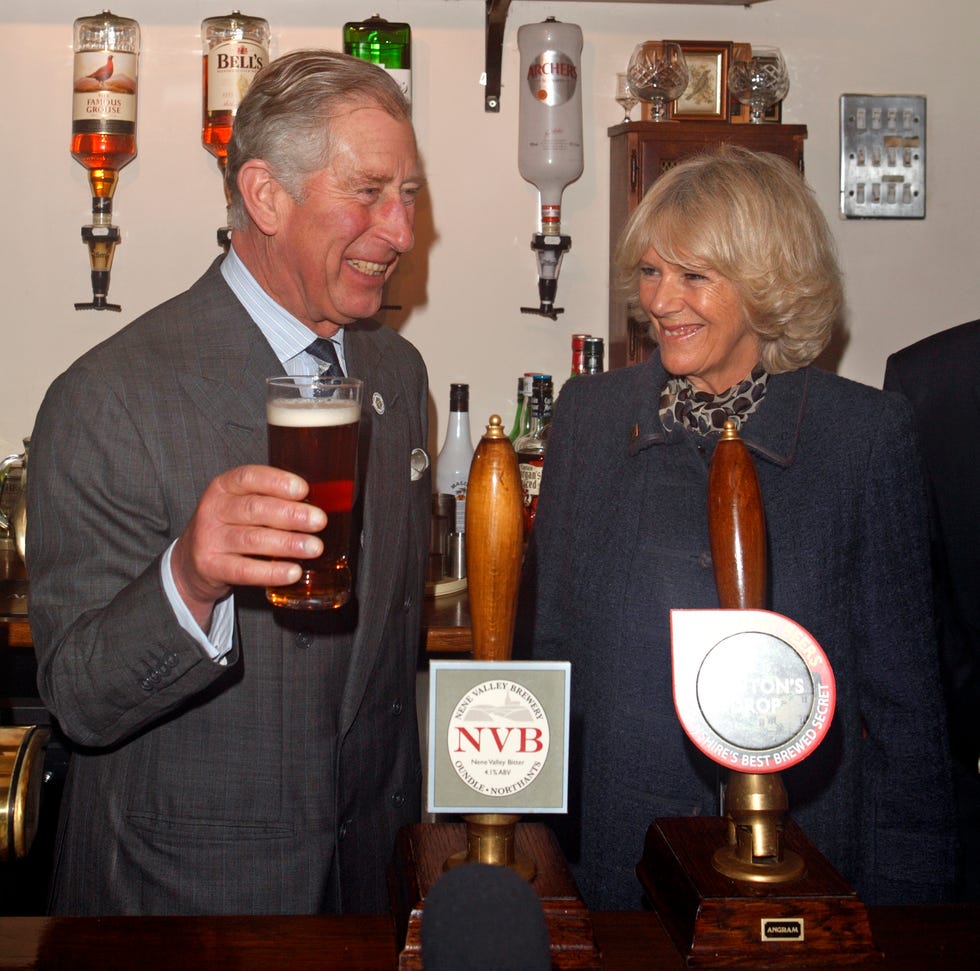prince charles, prince of wales pulls a pint of newtons drop beer as camilla, duchess of cornwall looks on