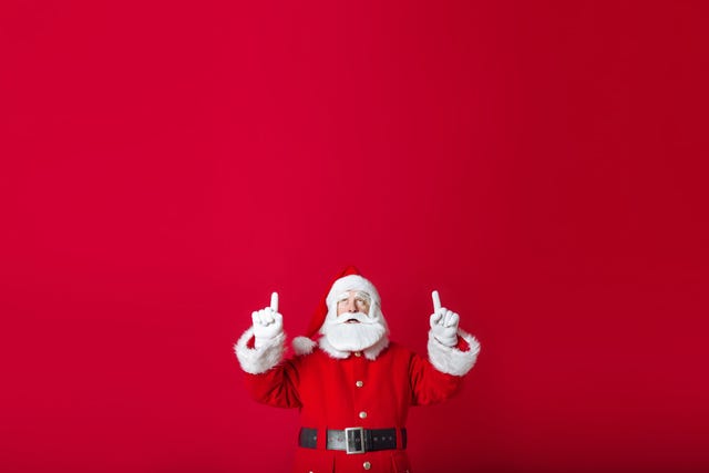 santa claus points his fingers up in copy space on a red background new year and christmas sale concept