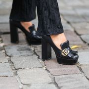paris, france   october 02 a guest wears a black flowing ribbed flared pants, black shiny leather fringed gg gold buckle block heels loafers  shoes from gucci, outside ester manas, during paris fashion week   womenswear spring summer 2022, on october 02, 2021 in paris, france photo by edward berthelotgetty images