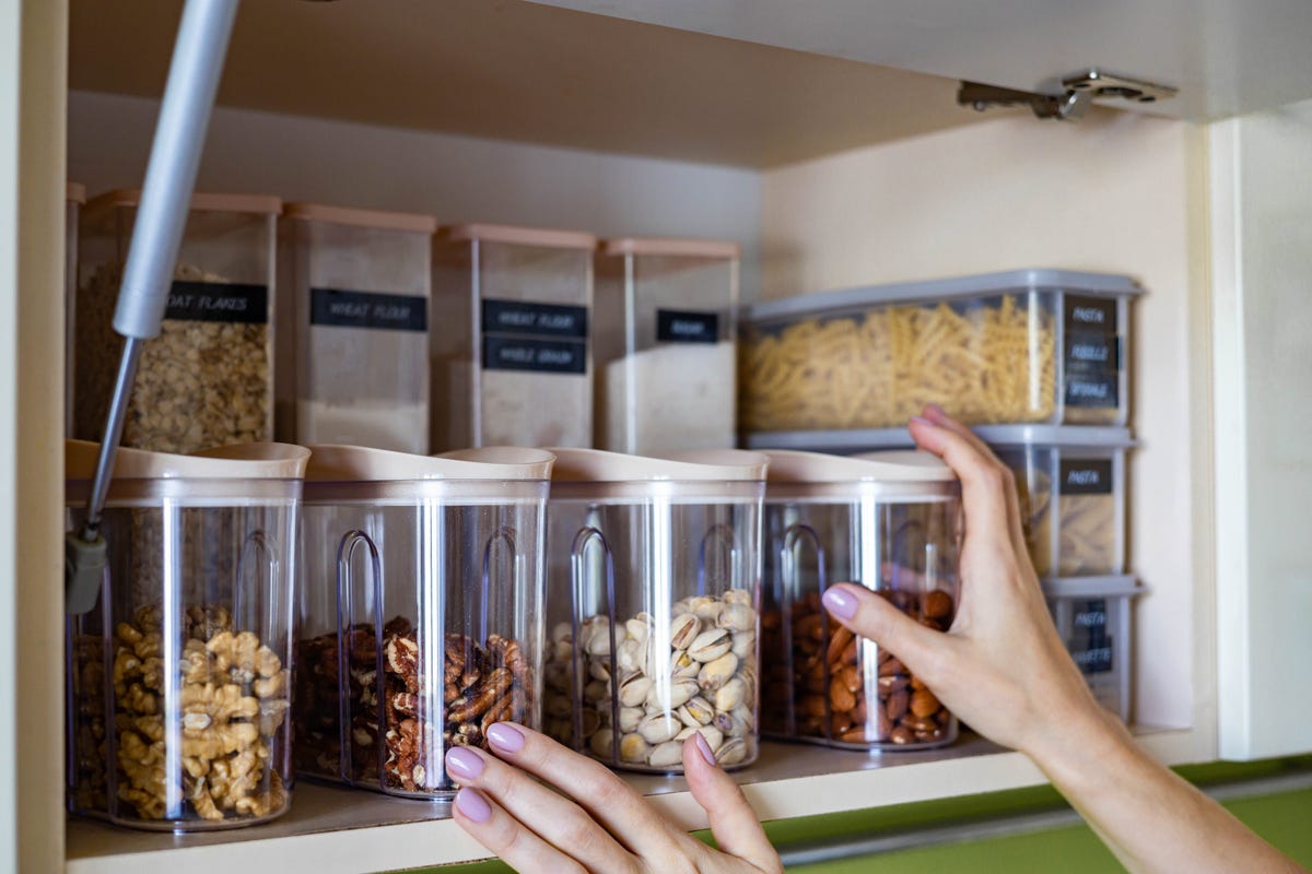 domestic healthy vegetarian dry food storage organization on shelf at kitchen cupboard. comfortable neatly keeping arrangement in glass containers oat flakes, wheat flour, sugar, pasta, nuts, rice