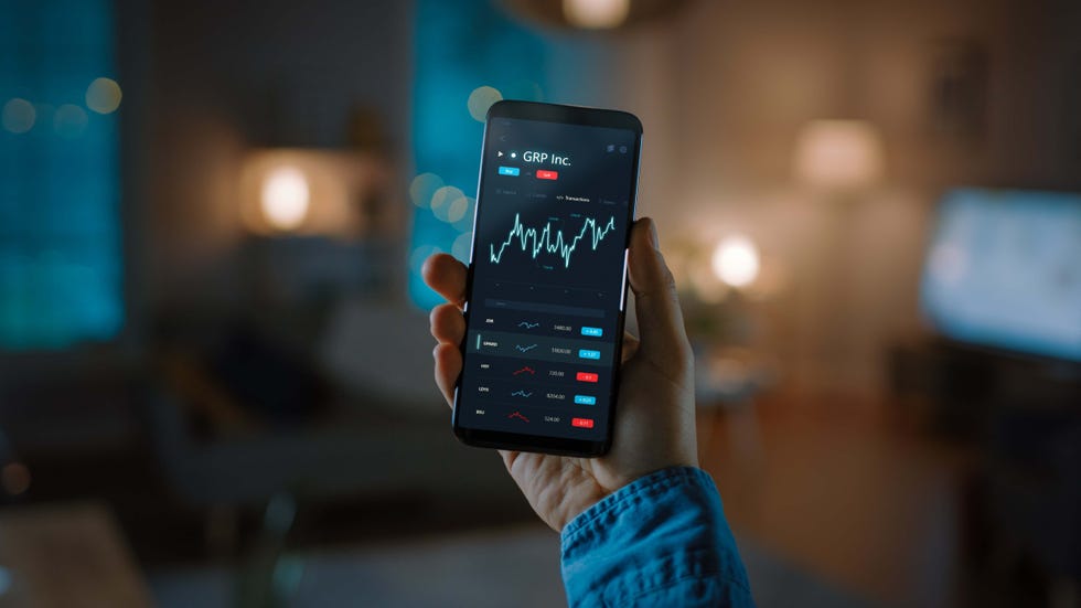 close up shot of smartphone man is using stock market app to check share prices graph is going up making a great profit in the background cozy homely atmosphere, dusk time