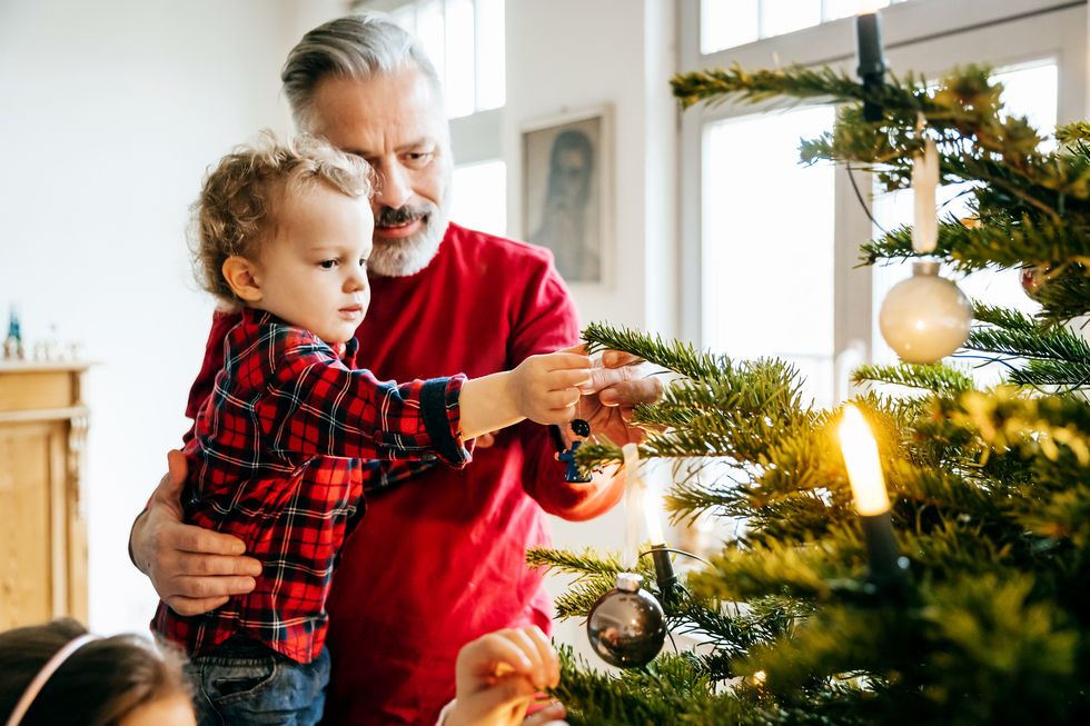 grandpa bonding with grandson while decorating christmas tree