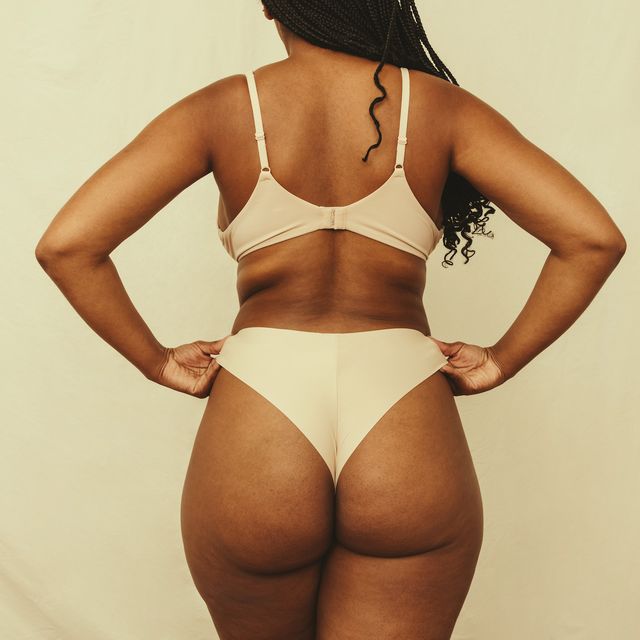 rearview of a self confident young woman adjusting her underwear in a studio anonymous young woman embracing her natural body and curves woman wearing beige underwear against a studio background
