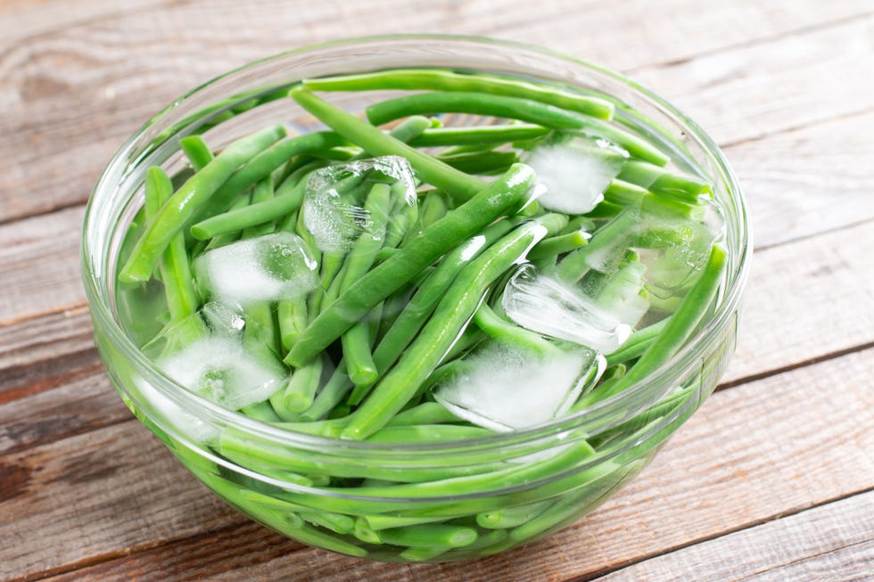 ways to use pickle juice blanch vegetables green beans in a colander. boiled or blanched vegetables in ice water on a wooden table