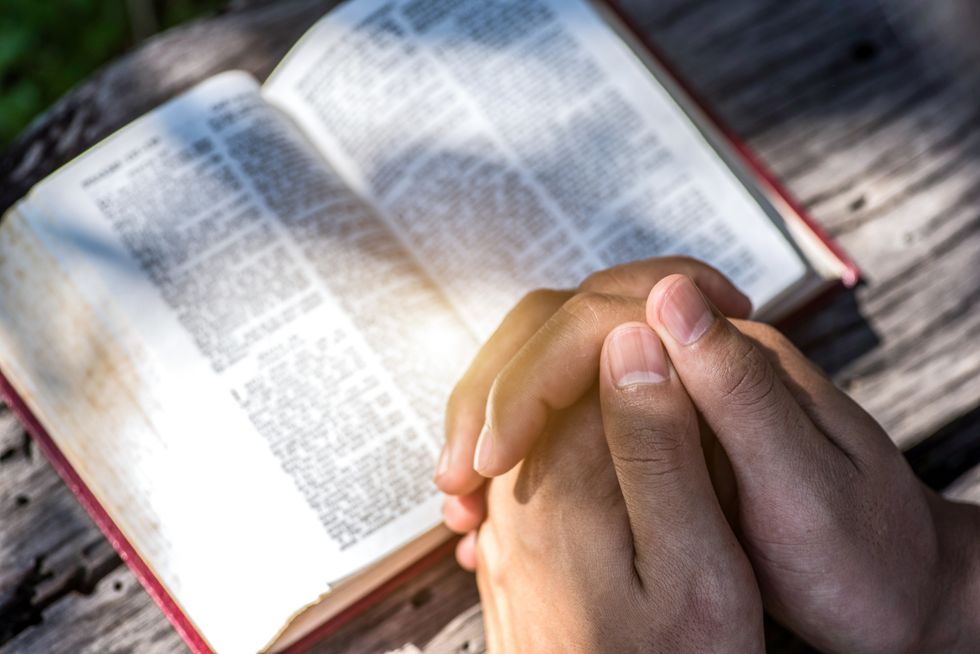 human hand placed on the bible, pray to god