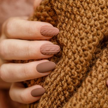 womens hands with fashionable manicure with a knitted texture on the background of a knitted scarf or plaid actual warm shades of autumn in manicure matte surface of nail polish horizontal photo