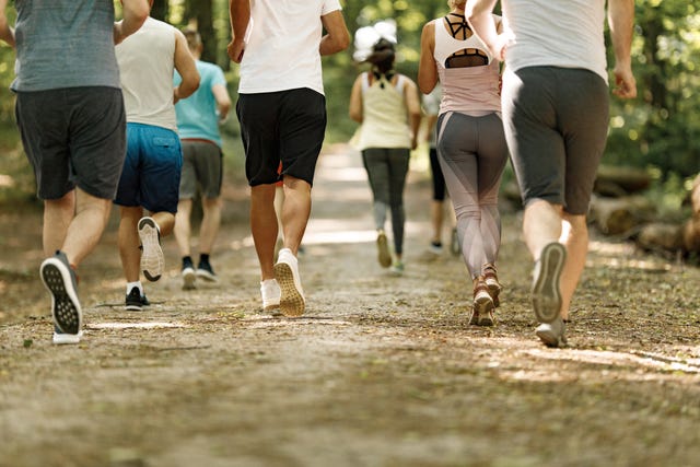 rear view of large group of unrecognizable athletes running a marathon in nature copy space