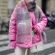paris, france   november 20 katie giorgadze katieone wears a pink knitted mohair sweater with feather sleeves from eleonora gottardi, a pink  gray  purple checkered print pattern wool oversized fringed scarf from acne studios, an oversized quilted pink shiny puffer jacket from choux, high waist white latte denim large pants from girlfriend, a vintage white latte smooth leather 5 à 7 hobo handbag from saint laurent, during a street style fashion photo session, on november 20, 2021 in paris, france photo by edward berthelotgetty images