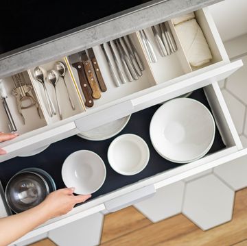 top view modern housewife tidying up kitchen cupboard during general cleaning or tidying up female neatly placing dishware and cutlery in drawer of table storage organization konmati method