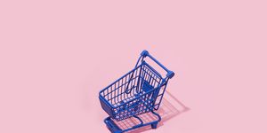 an empty blue shopping cart on a pink background with some blank space around it