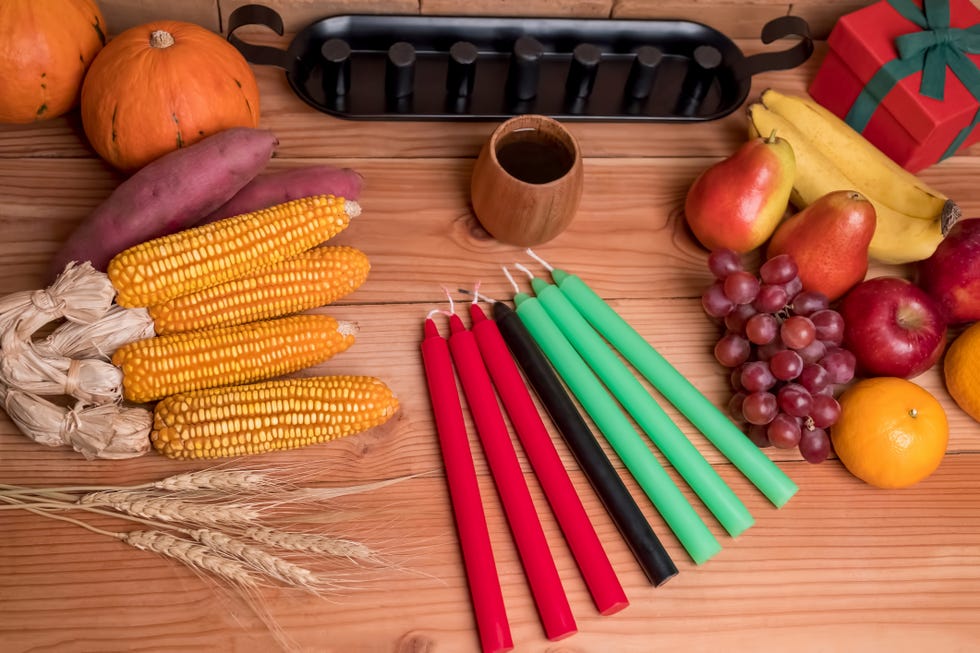 kwanzaa holiday concept with decorate seven candles red, black and green, gift box, pumpkin,corn and fruit on wooden desk and background