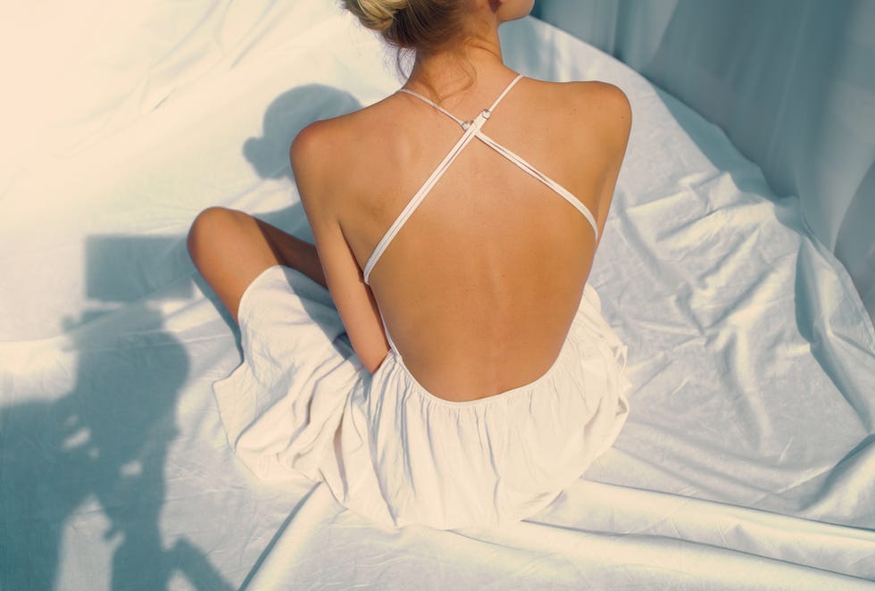 seductive woman in elegant dress posing for a photo. naked back with shadows