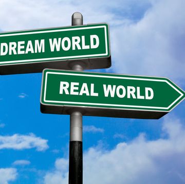two direction signs, one pointing left dream world, and the other one, pointing right real world