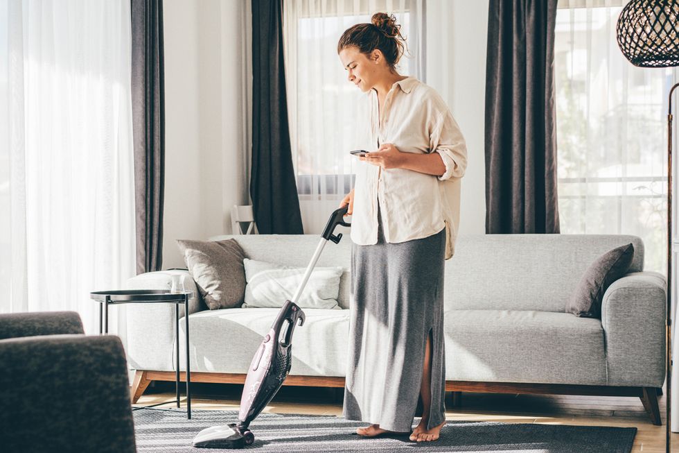 woman talking on cell phone while vacuuming floor