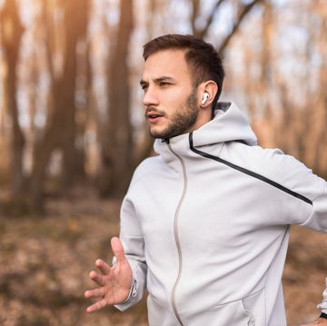 close up of athletic young man aj4 running outdoors and listening to music on wireless headphones