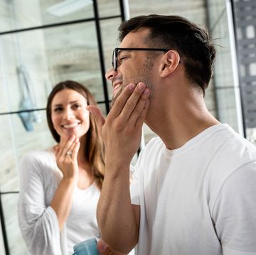 young couple going through morning routine in the bathroom applying face cream