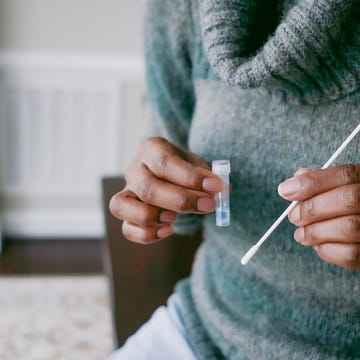 close up of unrecognizable black woman holding nasal swab and vial filled with reagent solution in preparation for at home covid test