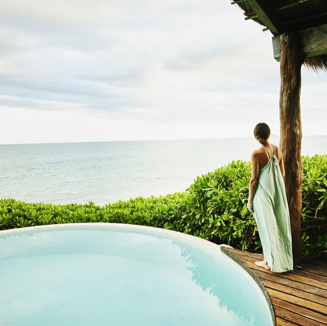 a person in a white dress standing next to a pool