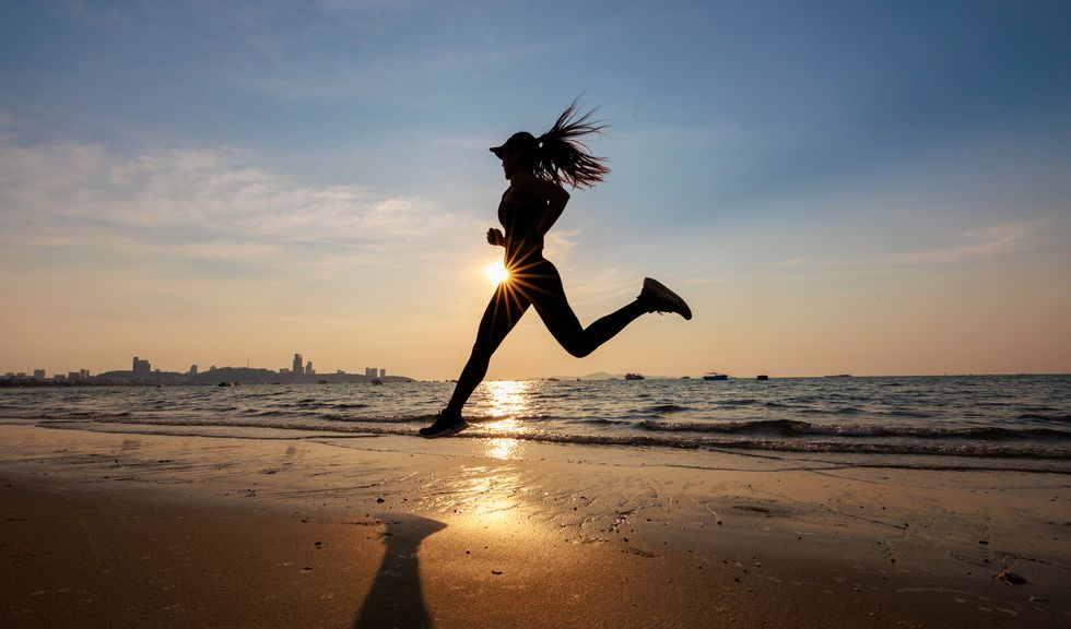 asian female running on the beach during sunset fitness and exercise concept