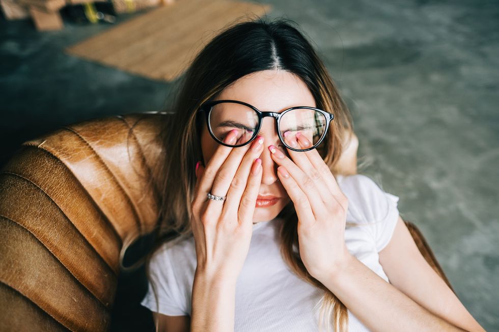 young woman rubs her eyes after using glasses eye pain or fatigue concept