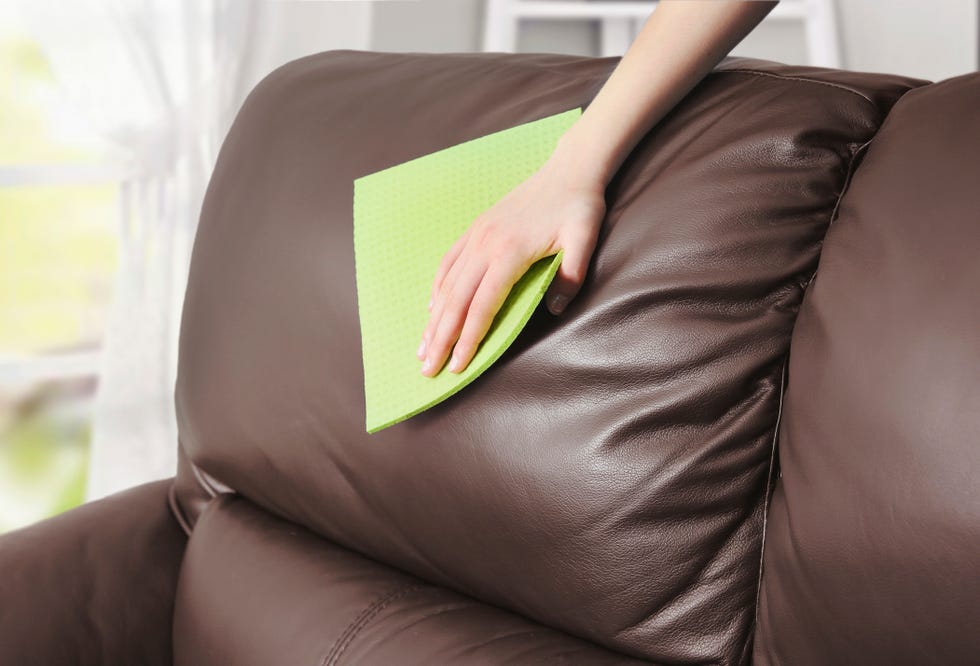 leather sofa cleaning, womans hand removes the dust with cloth from the firniture,clean the spot housekeeping