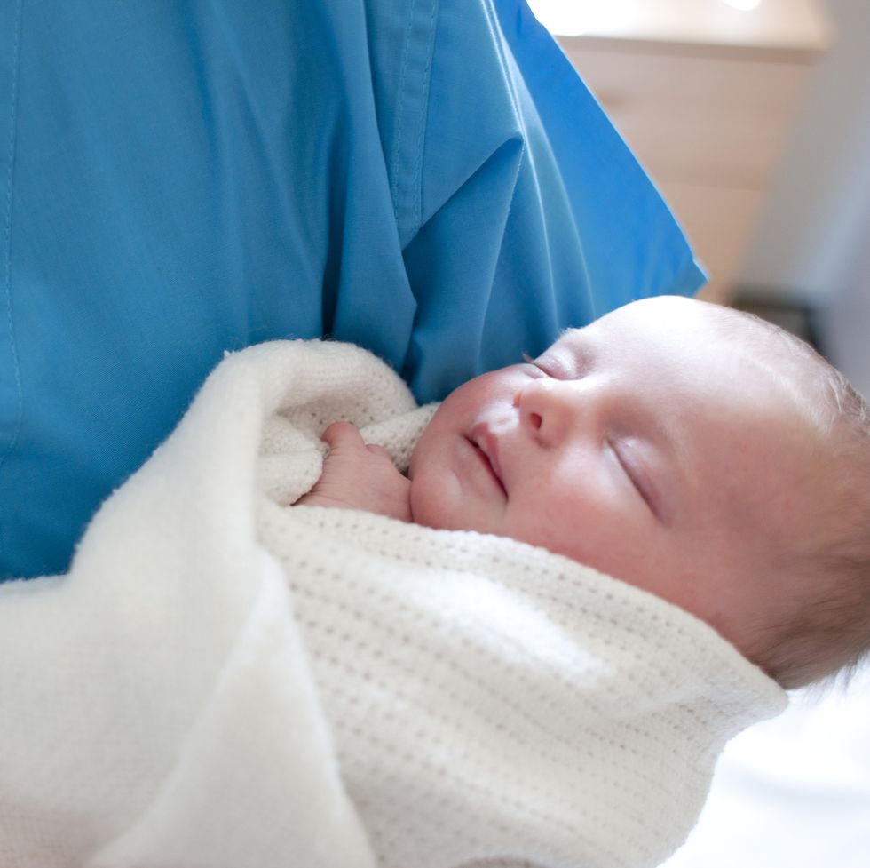 newborn baby held by a nurse