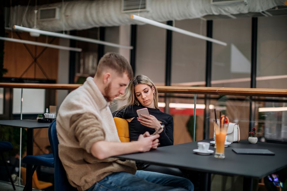 young couple in the restaurant using mobile phone