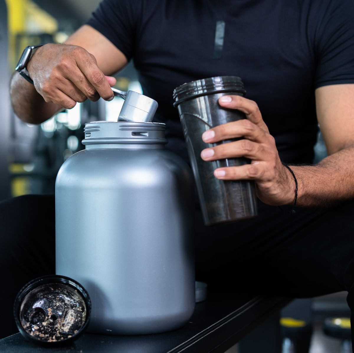 close up shot of bodybuilder hands taking protein powder and mixing with water on bottle by shaking at gym   concept of muscular gain, nutritional supplement and wellness