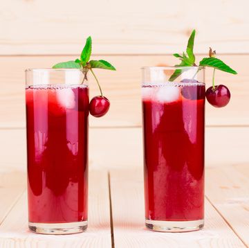 two tall glasses of tart cherry juice garnished with tart cherries