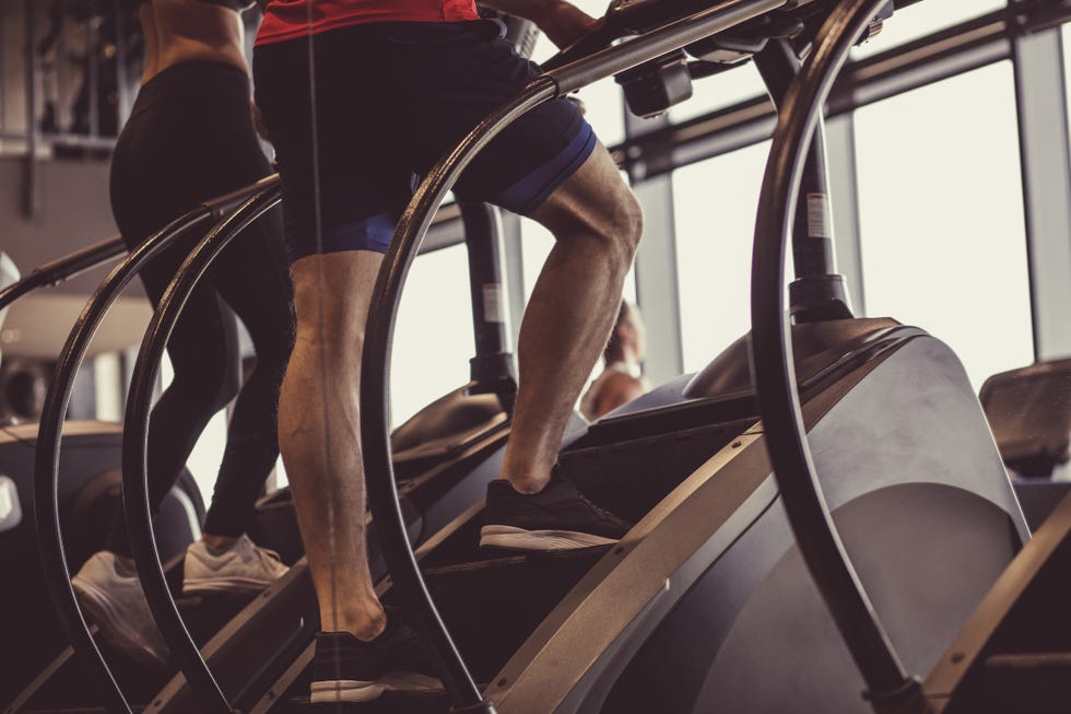 lower section of unrecognizable male athlete using stair climbing machine at the gym as a way of warm up before his work out