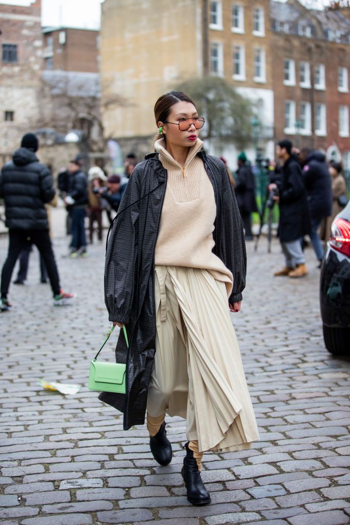 london, england   february 19 a guest is seen wearing beige jumper with zipper, pleated skirt, grey coat, green bag outside eudon choi during london fashion week february 2022 on february 19, 2022 in london, england photo by christian vieriggetty images