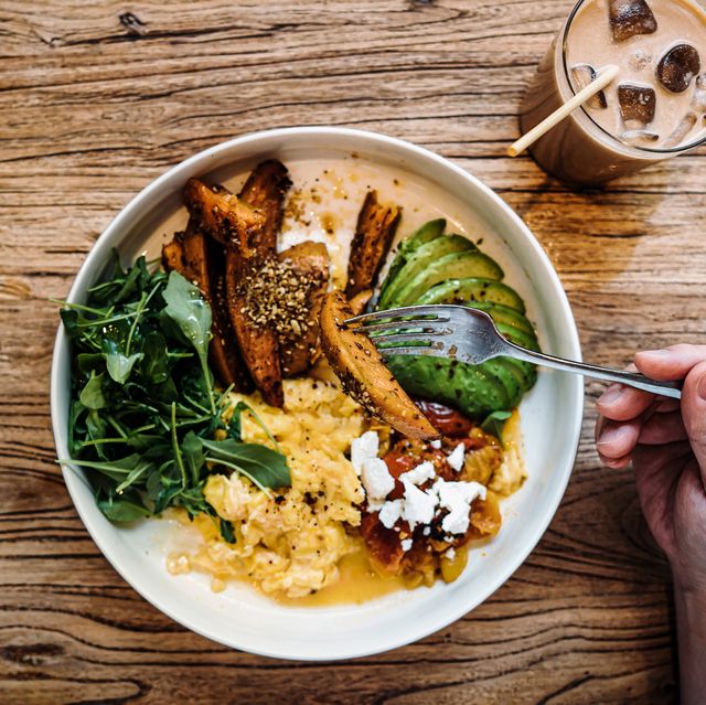 flat lay shot of man having healthy vegan green salad bowl for brunch in cafe table top view of a man eating breakfast with a glass of iced latte sitting at wooden dining table healthy eating lifestyle people, food and lifestyle concept